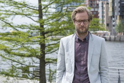 Anjes Tjarks in der HafenCity mit Baum im Hintergrund