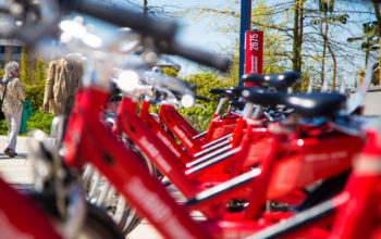 mehrere rote Leihfahrräder stehen aufgereiht hintereinander