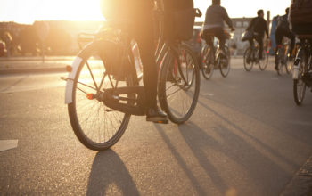 Rückansicht mehrerer Radfahrer, die bei Sonnenuntergang auf der Straße fahren