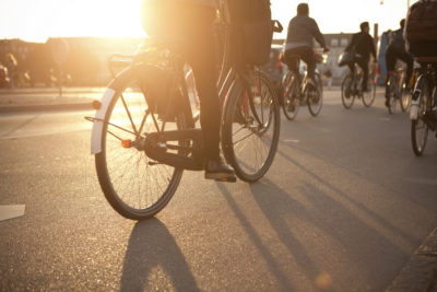 Rückansicht mehrerer Radfahrer, die bei Sonnenuntergang auf der Straße fahren
