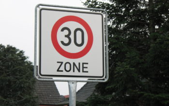 ein Verkehrsschild mit der Aufschrift "30 Zone", im Hintergrund Bäume